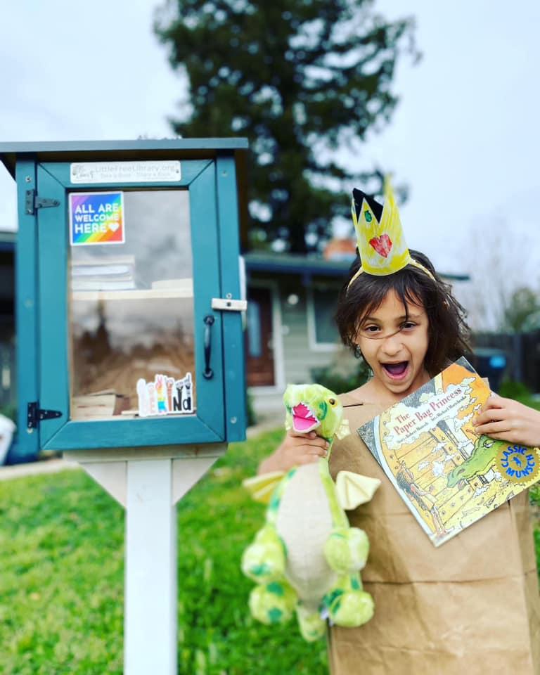 A child stands in front of a Little Free Library. They discovered a book that will open their imagination and fuel their curiosity.